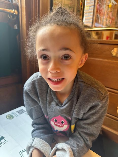 A little girl wearing a baby shark sweatshirt is smiling