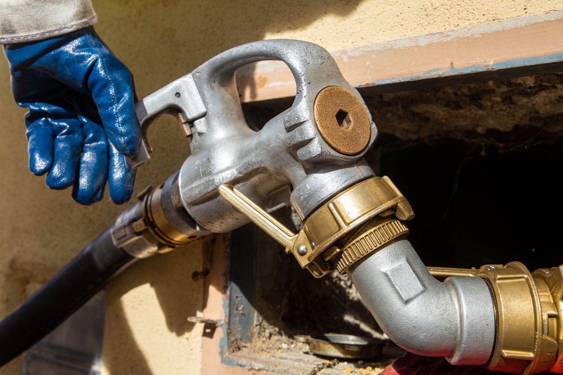 Main gantée de bleu tenant le pistolet de ravitaillement relié au réservoir.