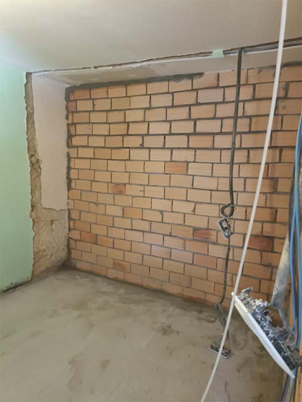 Una habitación con una pared de ladrillo y un ventilador en el suelo.