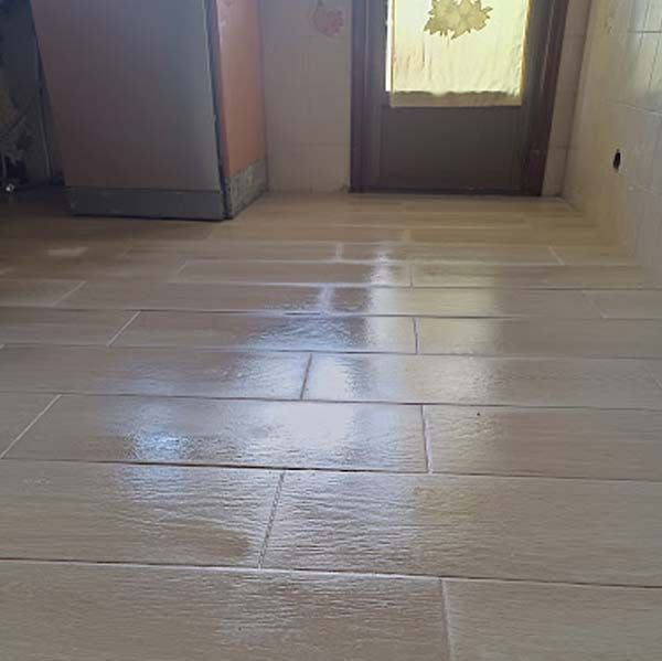 Un primer plano de un piso de baldosas en una cocina con una puerta al fondo.