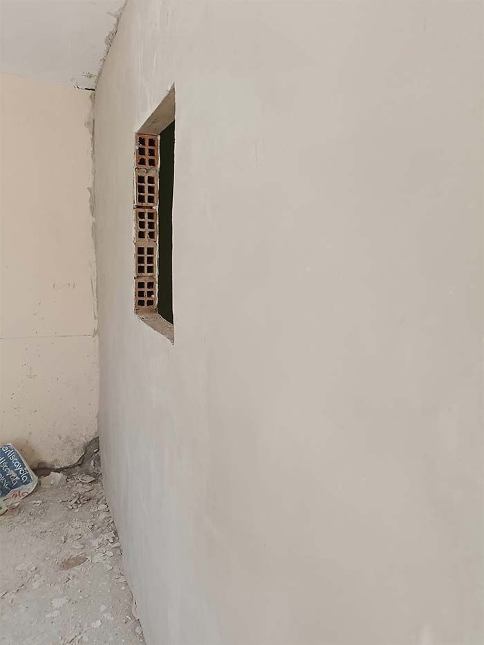 Una pared blanca con una pequeña ventana.