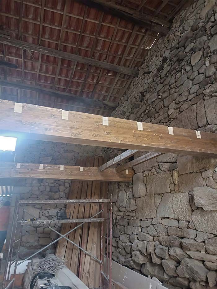 Una habitación con pared de piedra y vigas de madera.