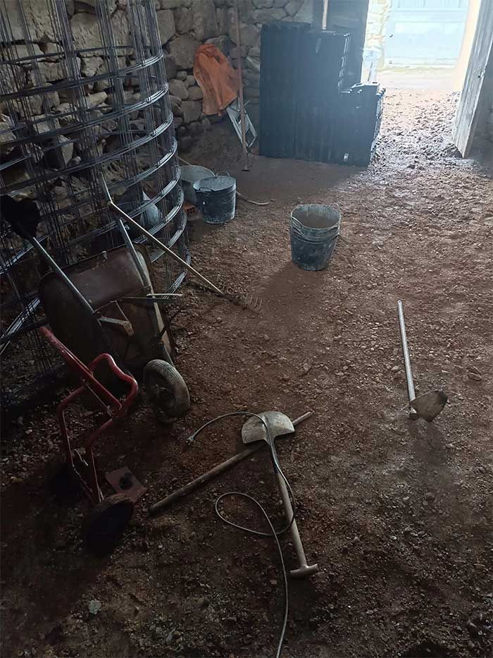 Una habitación con una carretilla, una pala y un cubo en el suelo.