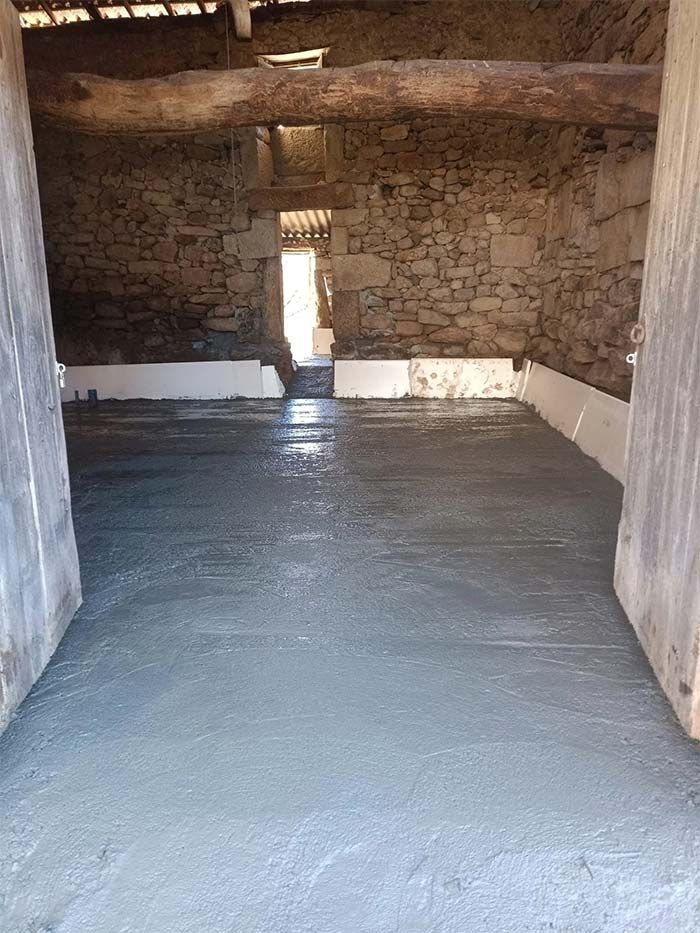 Una habitación con suelo de hormigón y pared de piedra.