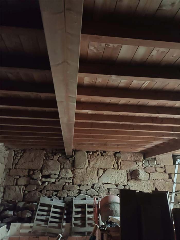 Una habitación con techo de madera y pared de piedra.