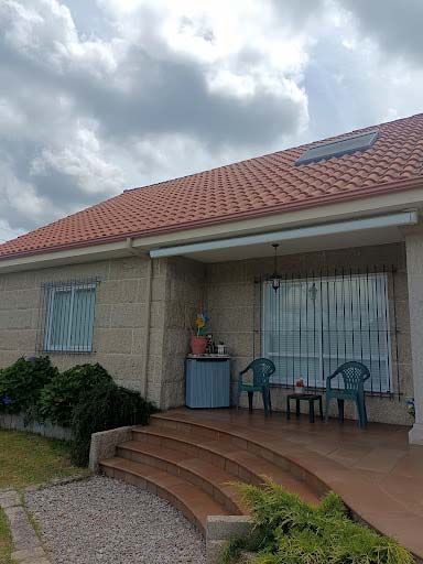 Una casa con techo de tejas rojas y un patio con sillas y mesas.