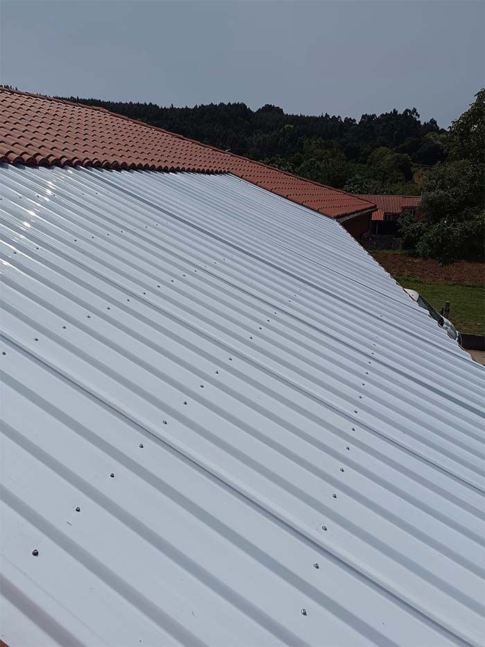 Un techo de metal blanco con un techo de tejas rojas al fondo