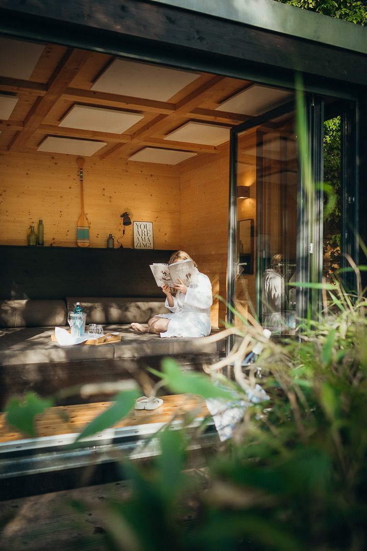 Eine Frau sitzt auf einem Sofa im Wohnzimmer und liest ein Buch.