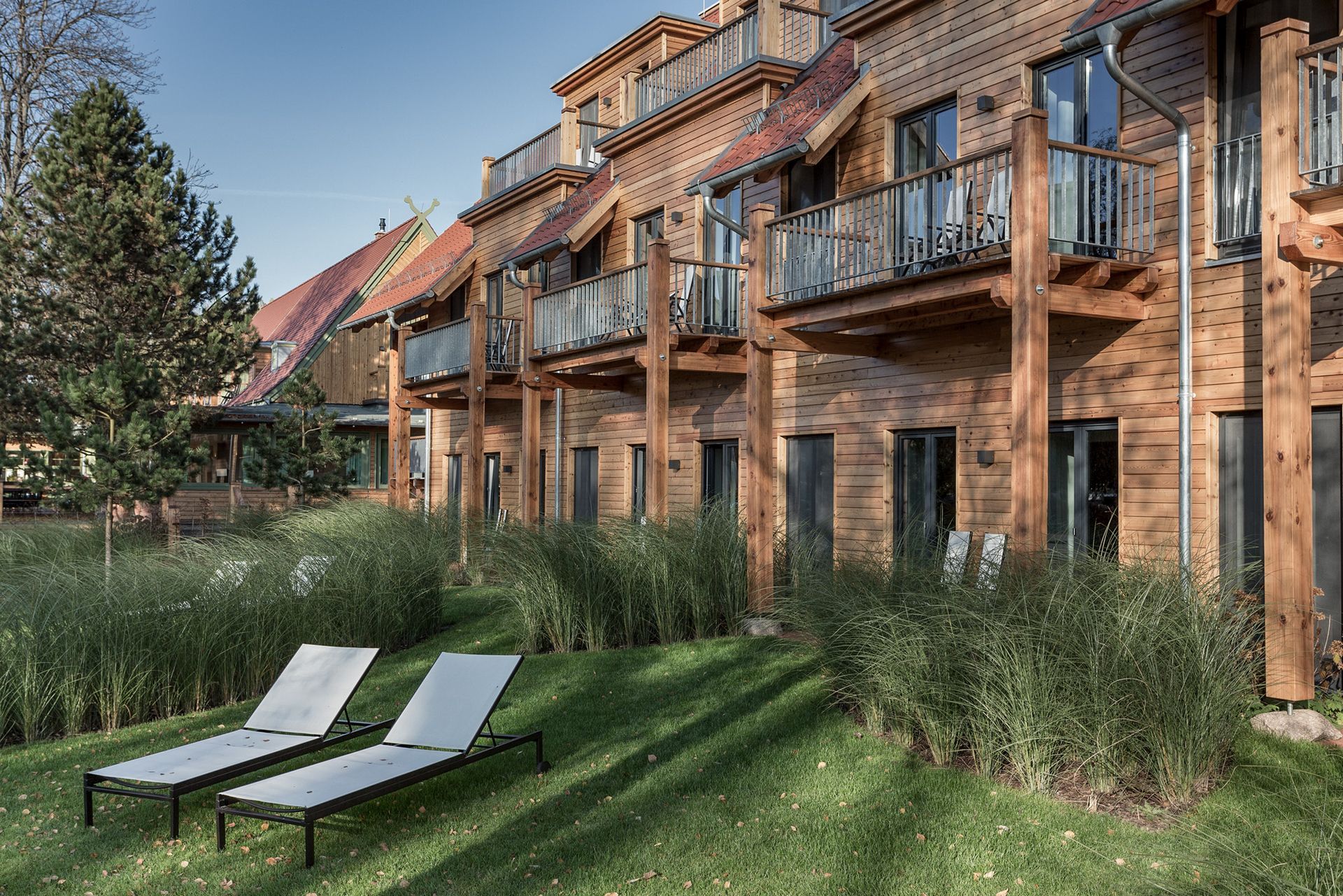 Zwei Liegestühle stehen im Gras vor einem Holzgebäude.