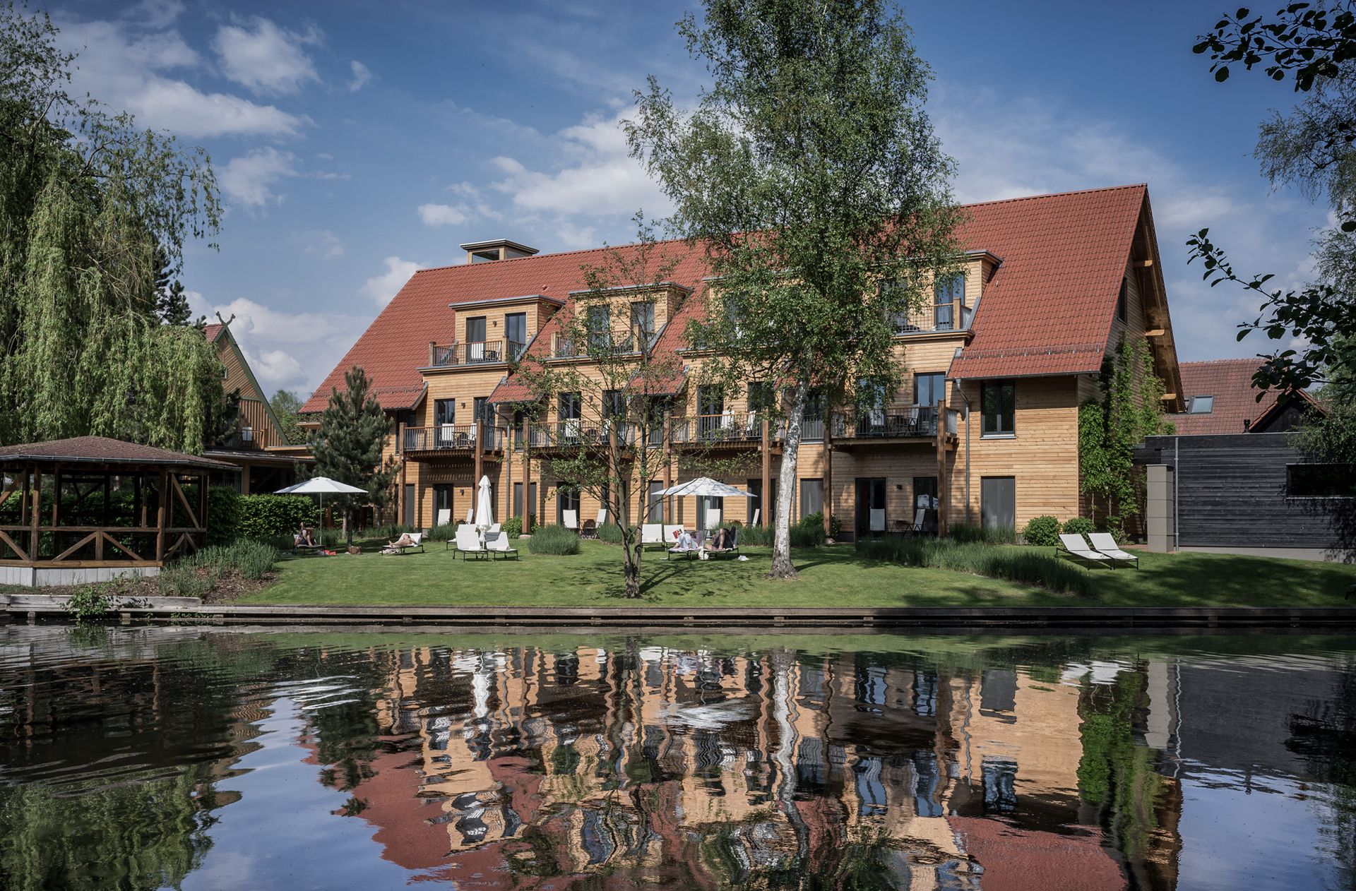 Ein großes Haus mit einem roten Dach steht neben einem Gewässer.