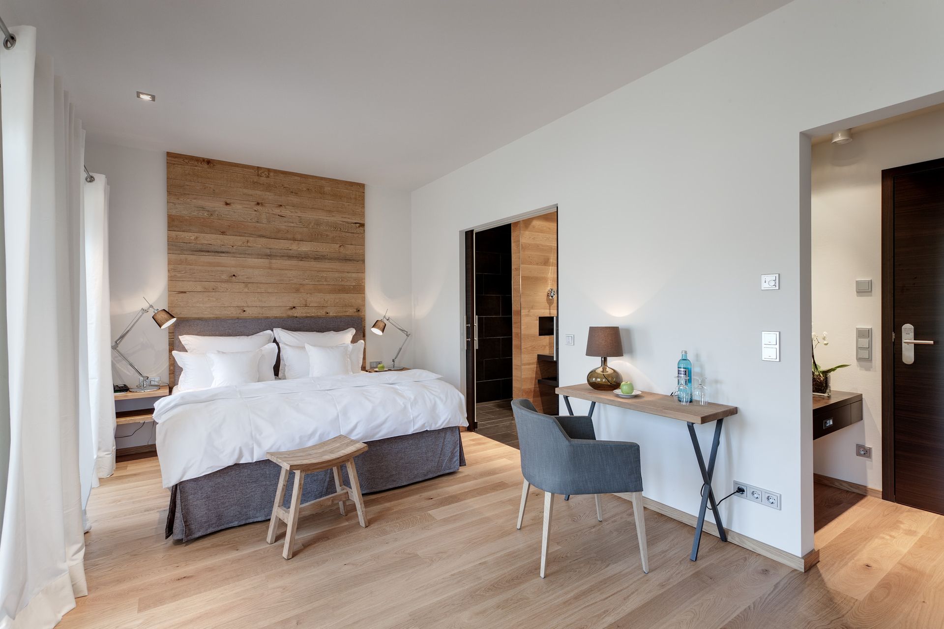 Ein Hotelzimmer mit großem Bett, Schreibtisch und Stuhl.