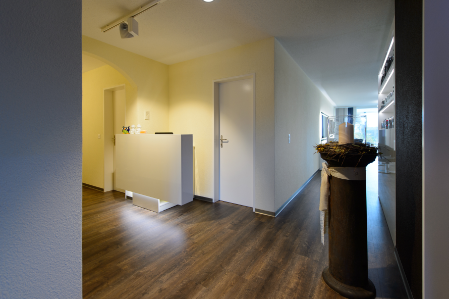 Ein Flur mit Holzboden und einer weissen Theke. Foto von Coiffure Sunshine