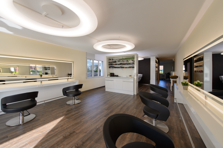 Ein Friseursalon mit vielen Stühlen und einem grossen Spiegel. Foto von Coiffure Sunshine