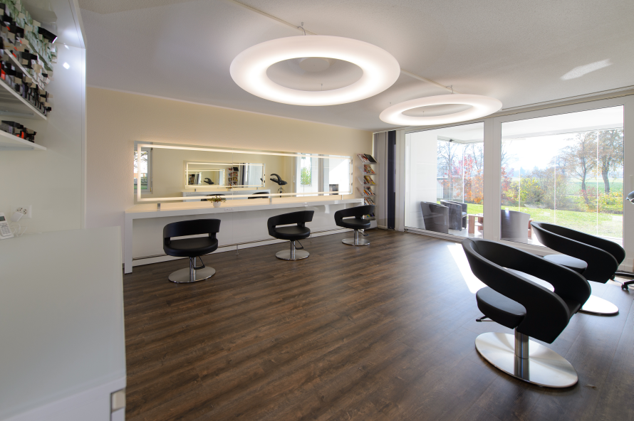 Ein Friseursalon mit vielen Stühlen und einem grossen Spiegel. Foto von Coiffure Sunshine