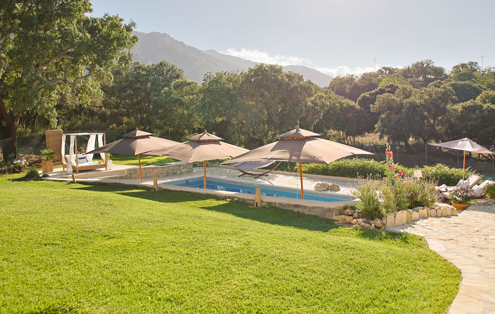 Large lawn leading to the pool with parasols and canopy daybed