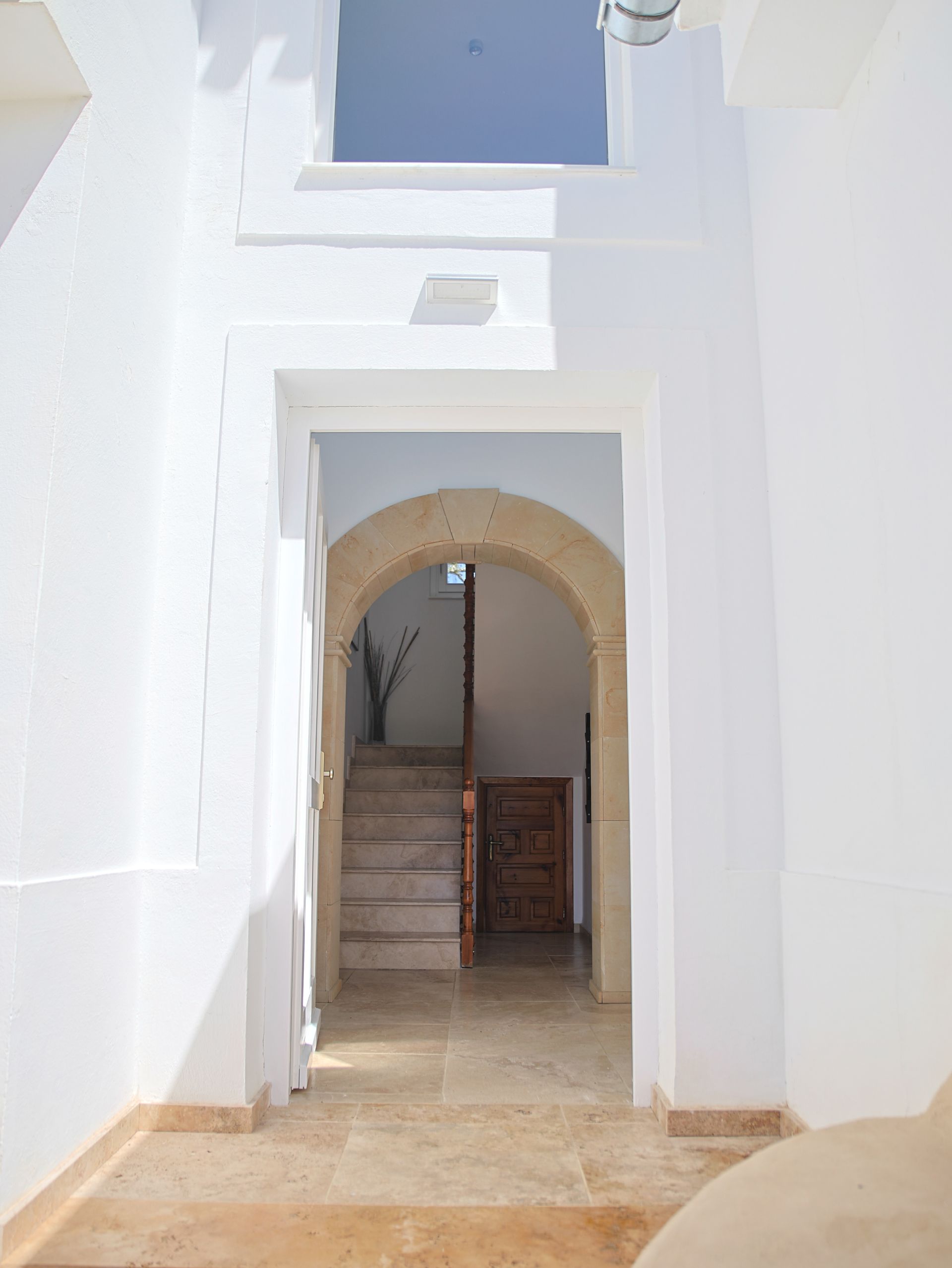 White Andalusian facade with arched passage and blue sky