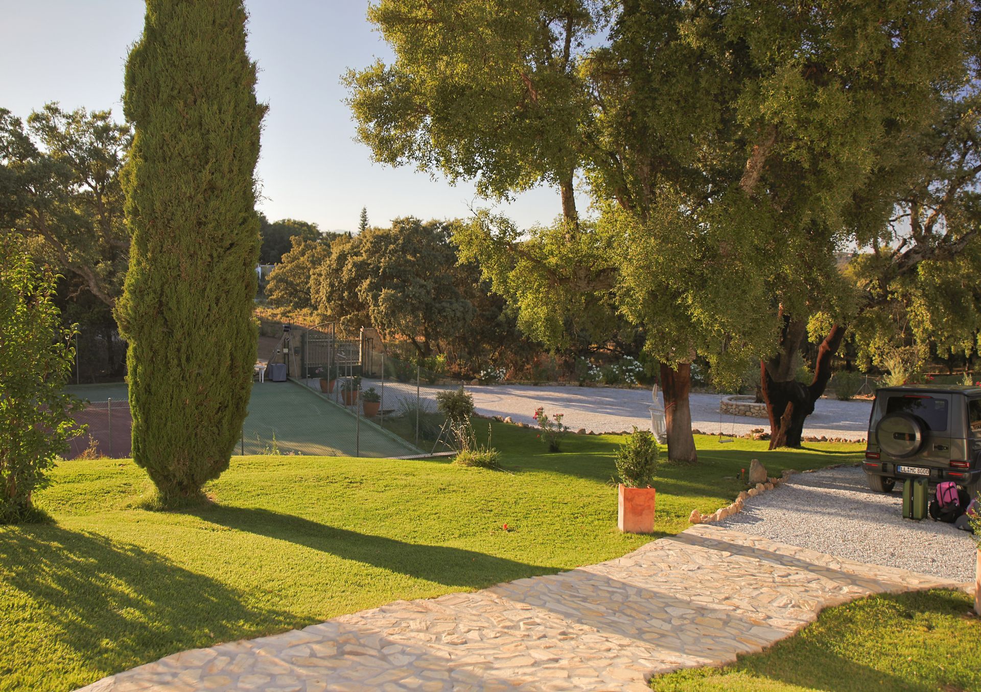 Garden with cypress, lawn and gravel driveway on the private estate