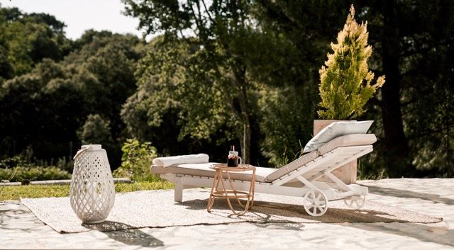White sun lounger with lanterns on a stone terrace in the garden