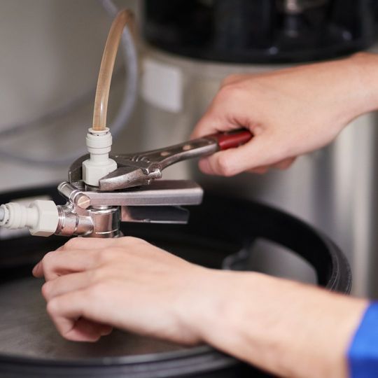 Una persona está trabajando en un barril de cerveza con una llave inglesa.