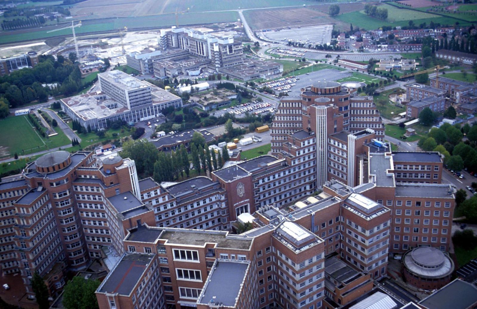 Une église historique en briques, ornée d'une rosace imposante, d'une porte cintrée et d'une haute flèche en pierre, se détachant sur un ciel nuageux.