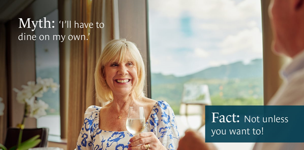 Woman smiling, holding wine glass, next to person. 