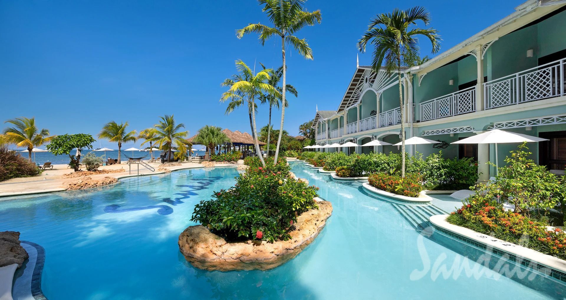 Pool and resort with a blue sky, palm trees, and white umbrellas.