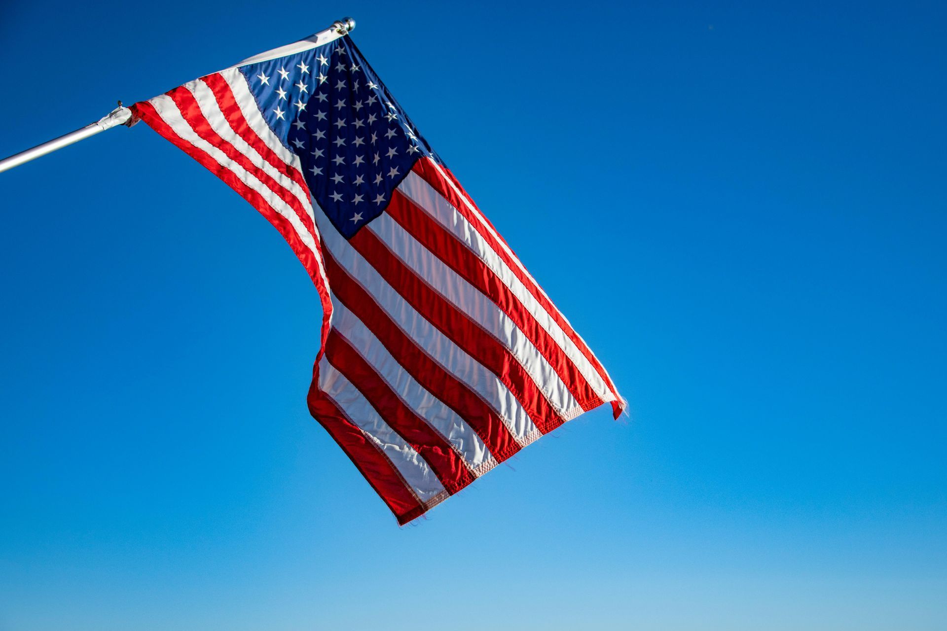 American flag waving against a bright blue sky.