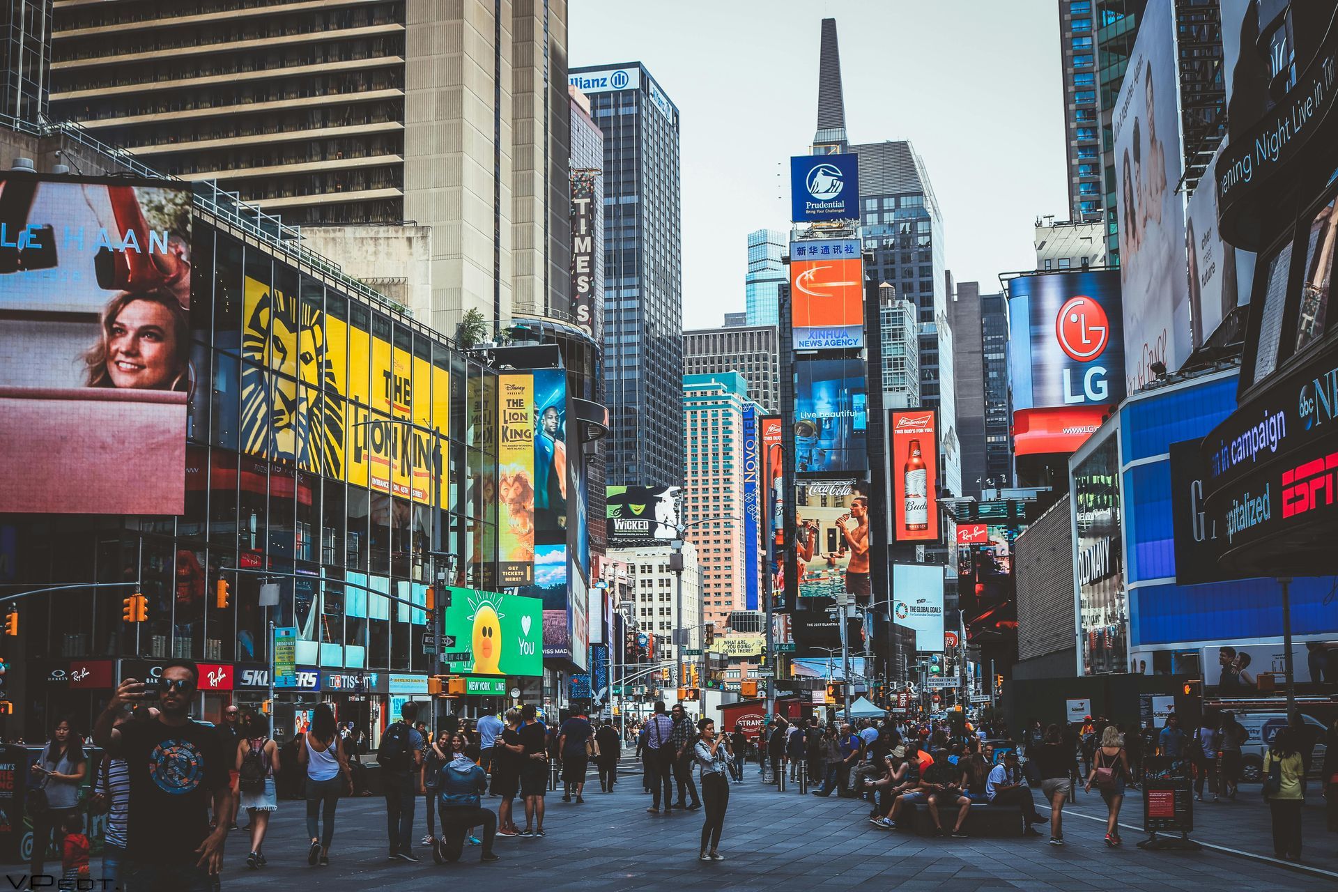 Busy Times Square with crowds, tall buildings, and colorful billboards.