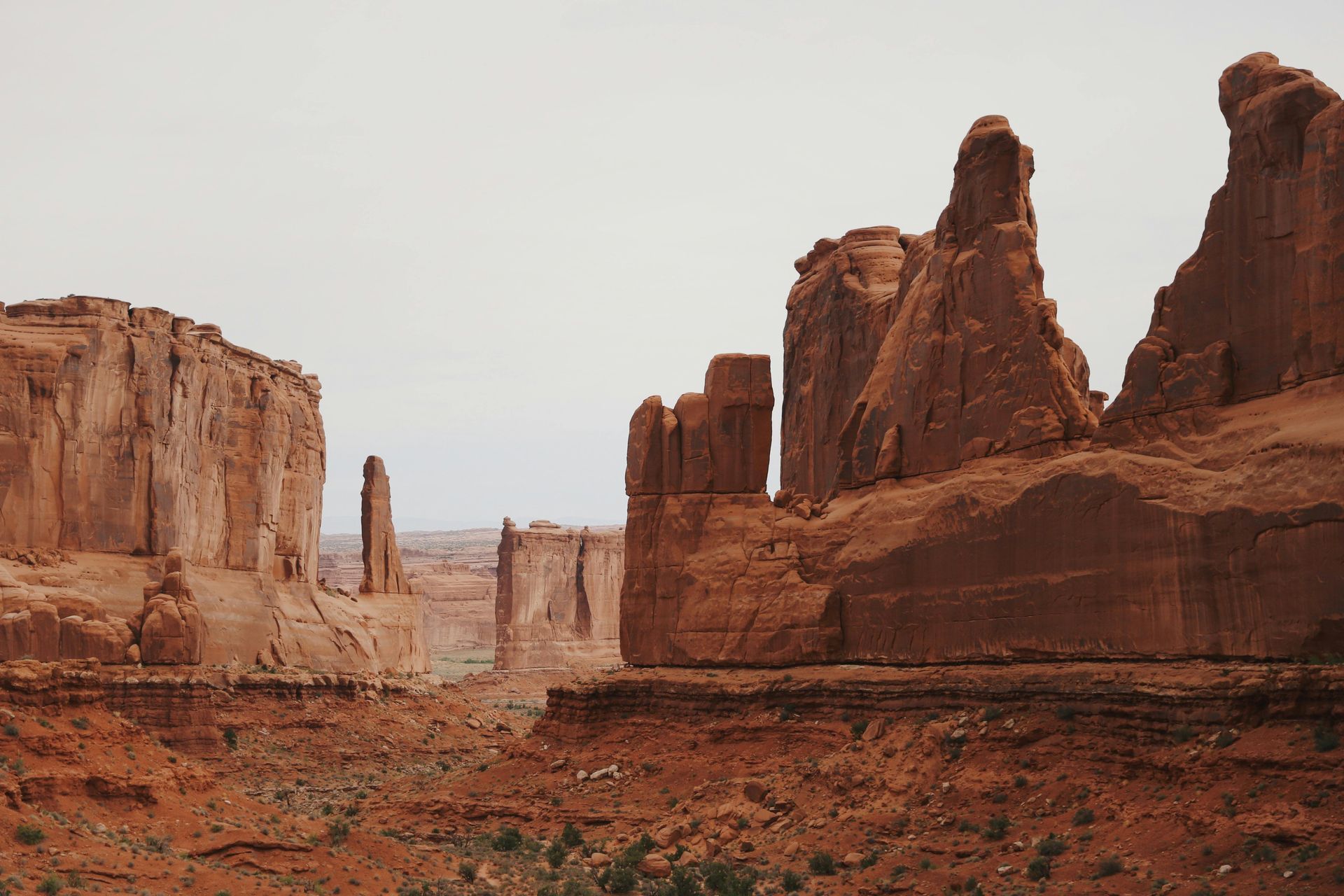 Red rock formations in an arid desert landscape under a cloudy sky.