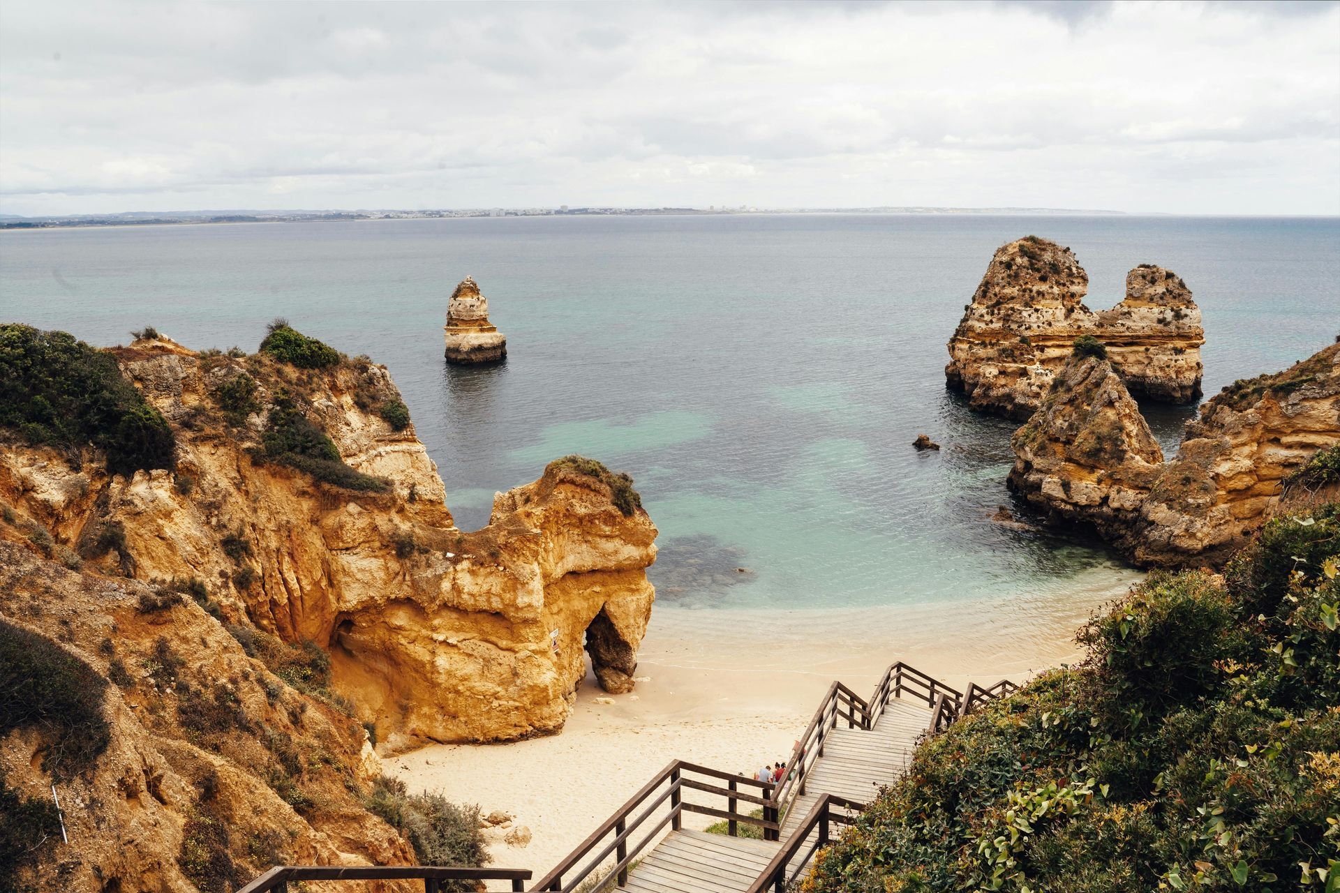 A wooden staircase leading to a beach with rocks in the water