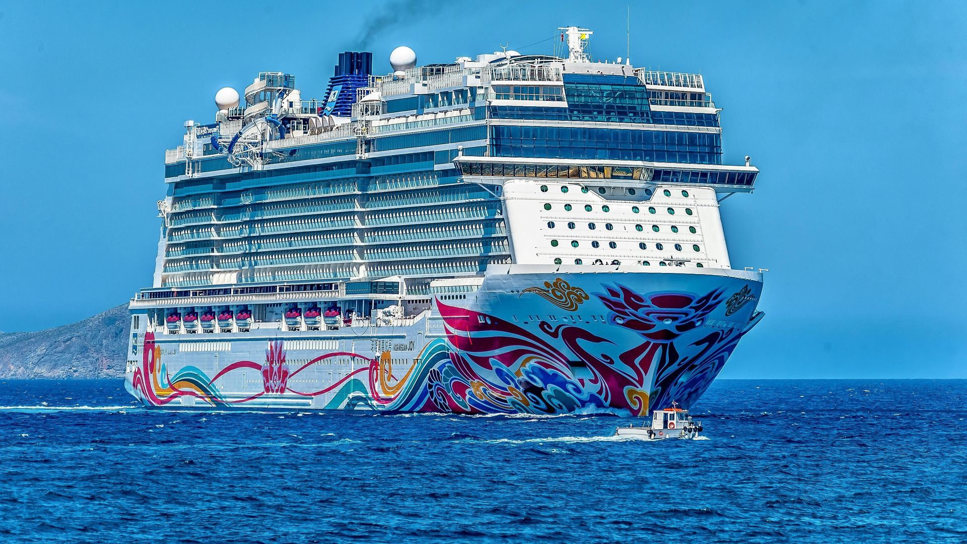 Cruise ship with colorful artwork sailing on blue water.