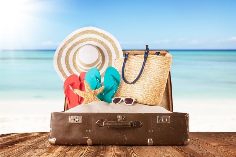 A suitcase filled with beach items on a wooden table.