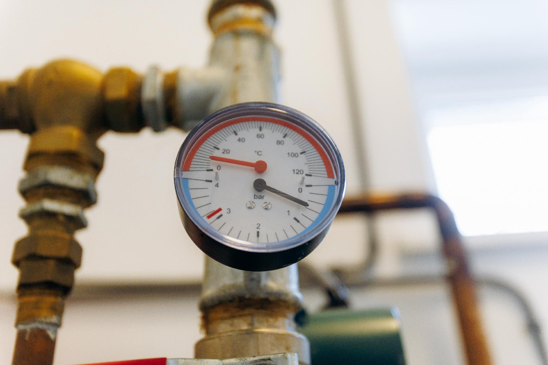Rundes Manometer an einem Messingrohr, das in einer industriellen Umgebung einen niedrigen Messwert anzeigt