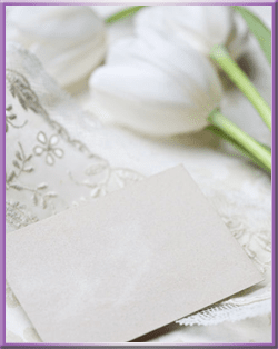 Cartão em branco sobre renda, com tulipas brancas em foco suave.