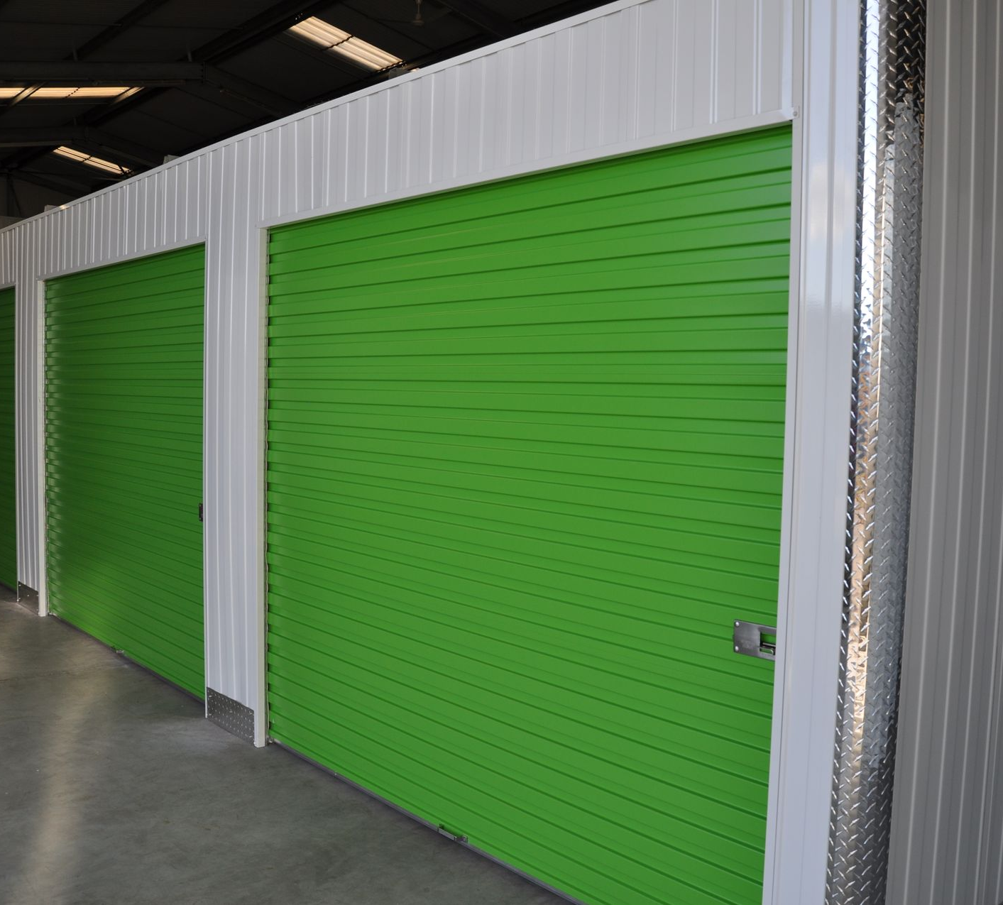 Portes vertes de box de stockage dans un bâtiment blanc et argenté.
