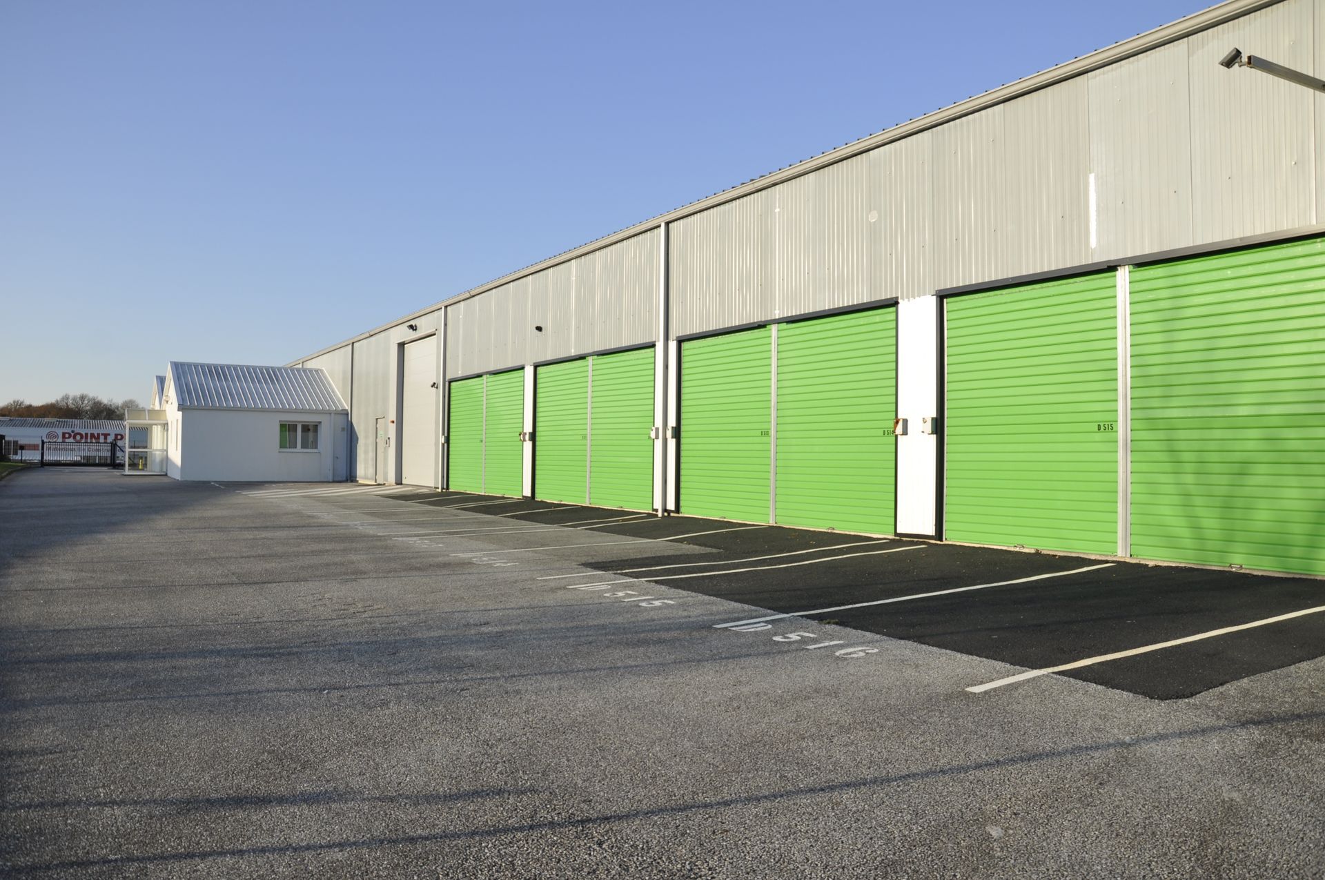 Réception d'un entrepôt de stockage avec murs verts, chaise noire et plante. Les panneaux indiquent BOUTIC'BOX et TOUT EN BOX.