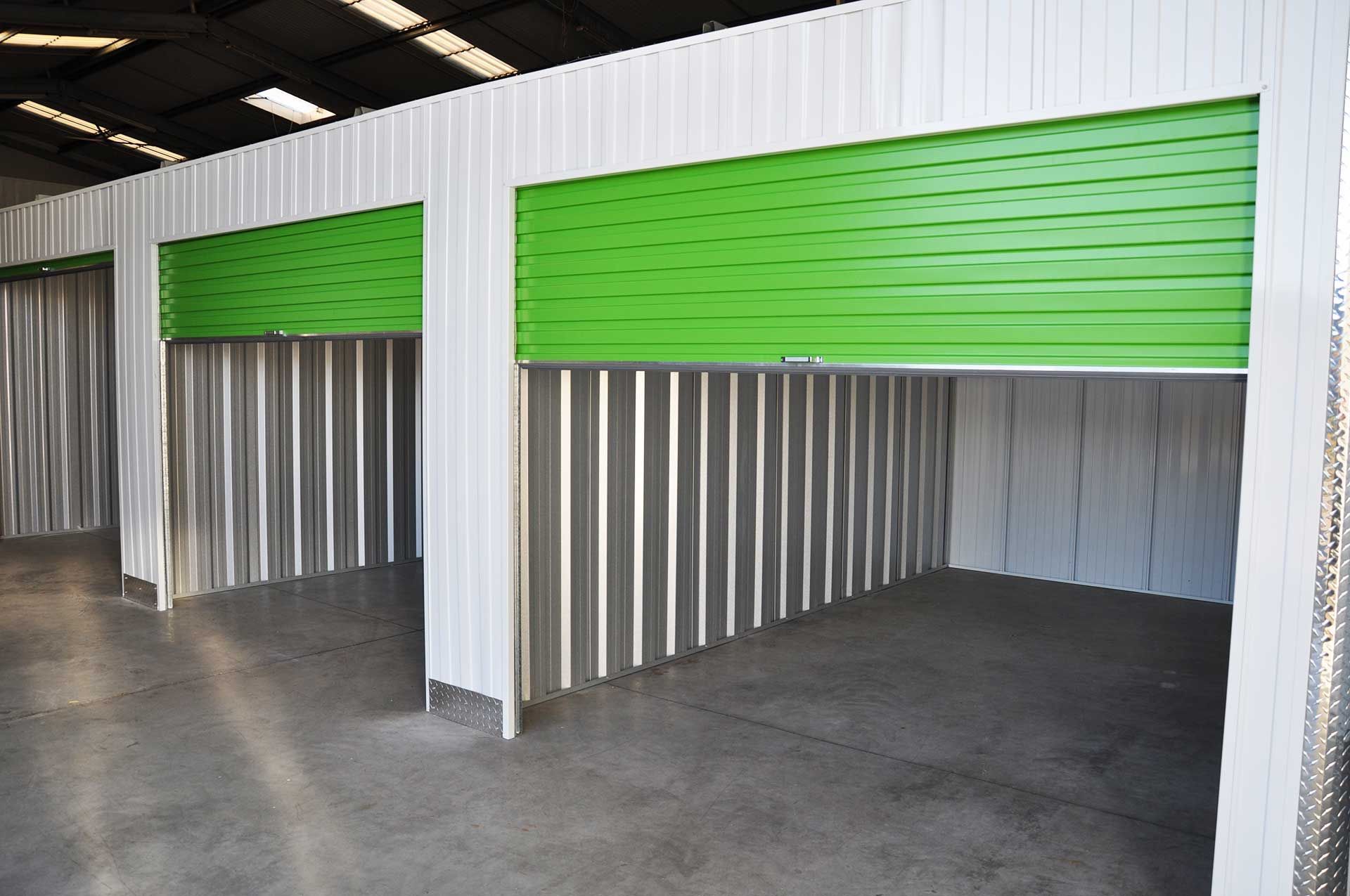 Fresque murale sur un bâtiment de stockage : des cartons, une machine à laver, un ours en peluche, un box de stockage ouvert rempli de cartons, un colibri.