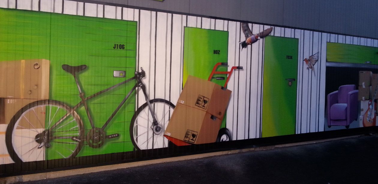 Fresque : portes vertes, vélo, carton sur un diable, oiseaux et boîtes.