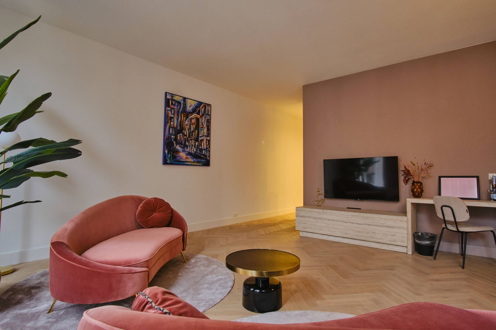 A living room with a pink couch , coffee table , and television.