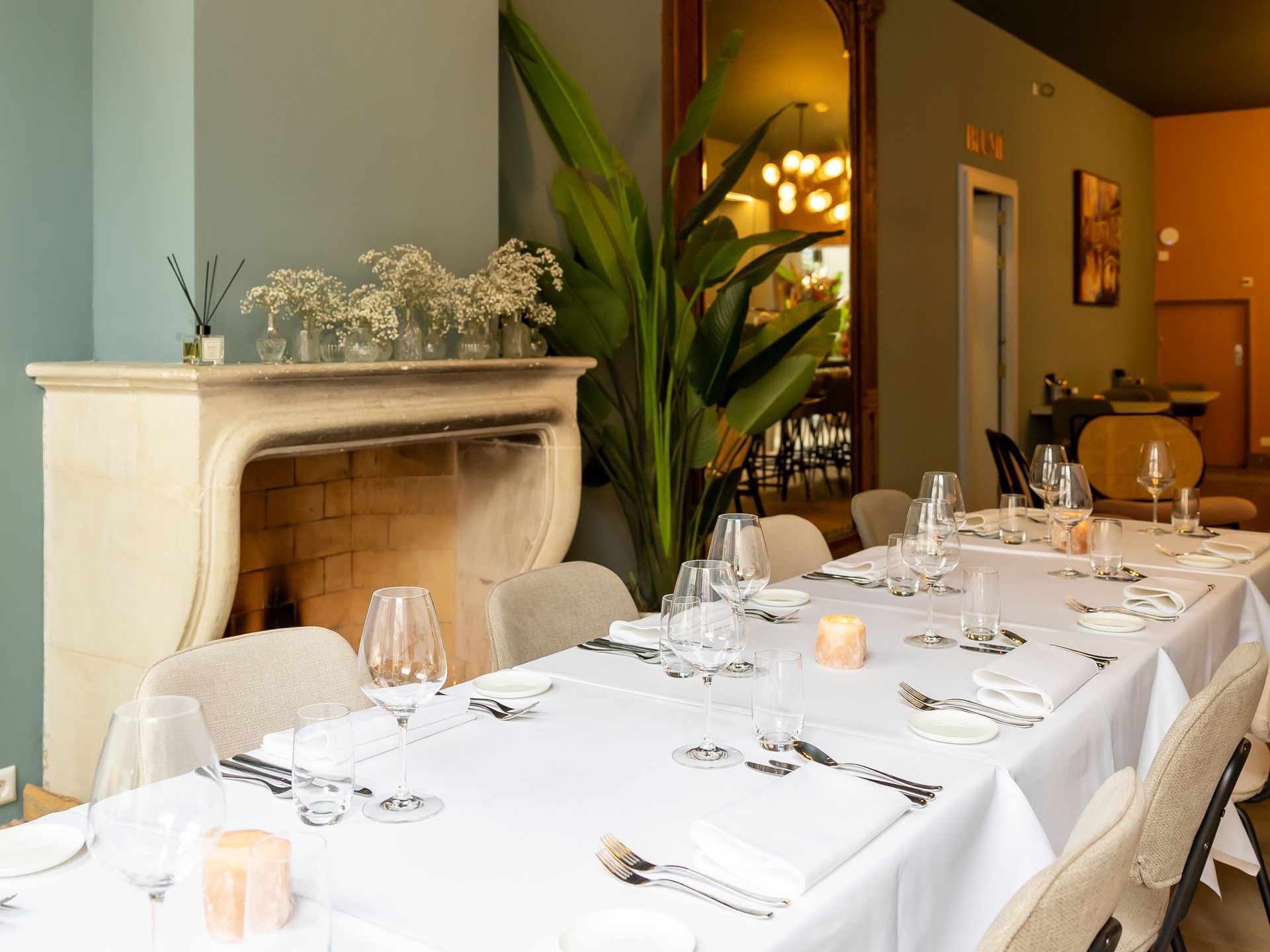 Twee jonge meisjes zitten op een groot bed in een hotelkamer. Het bed heeft een perzikkleurig hoofdeinde. Er staat een rode stoel naast.