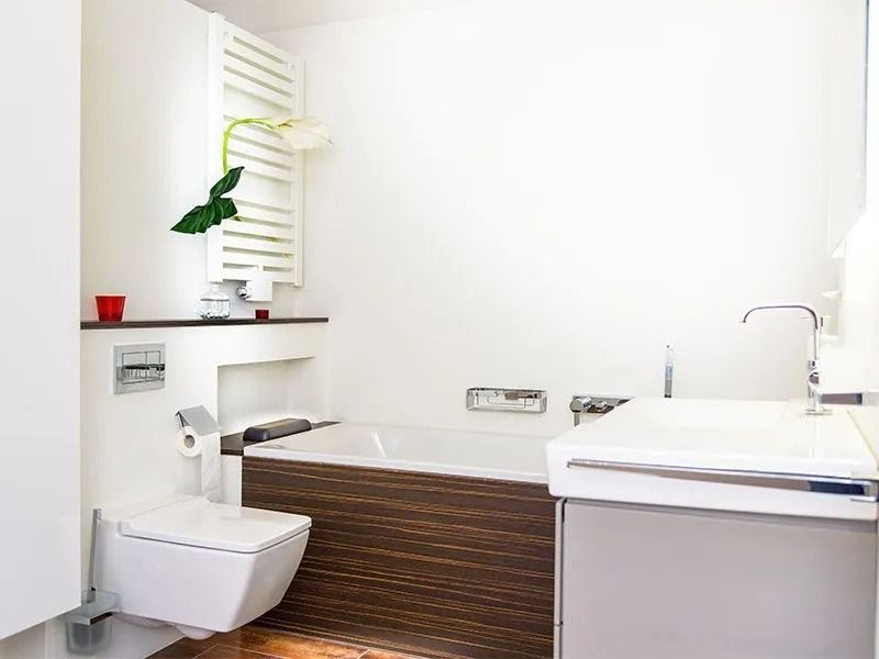 Helles modernes Badezimmer mit Badewanne, Waschtisch, Designheizkörper und minimalistischer Einrichtung.