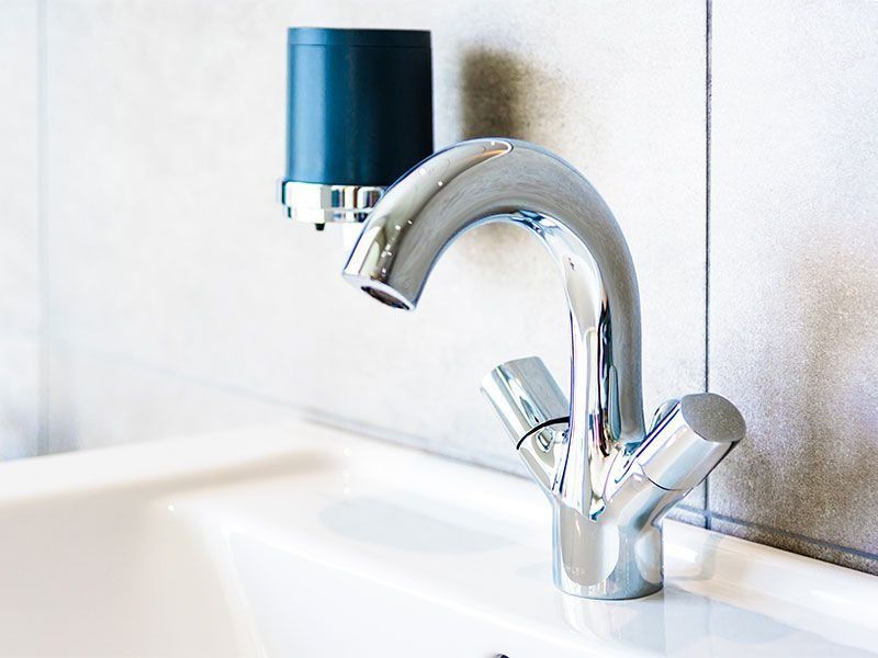 Verchromte Waschtischarmatur mit modernem Design und Seifenspender im Badezimmer.