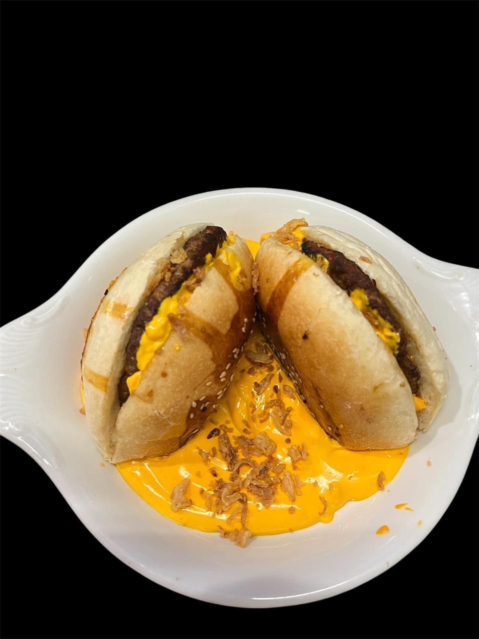 Zwei Hot Dogs mit Käse und Senf auf einem weissen Teller.