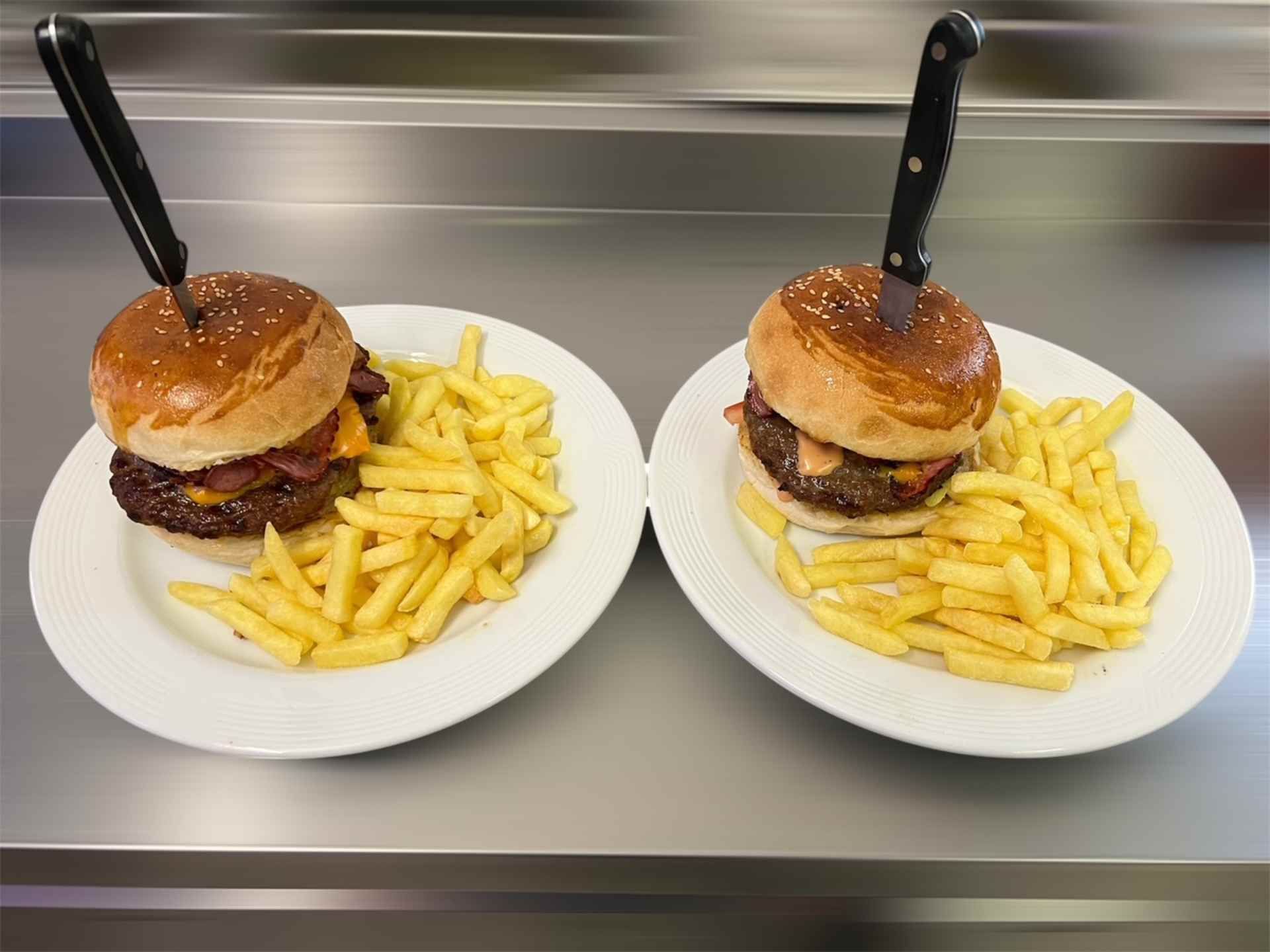 Ein Hamburger mit Käse, Speck, Salat und Tomaten auf einem weissen Teller.