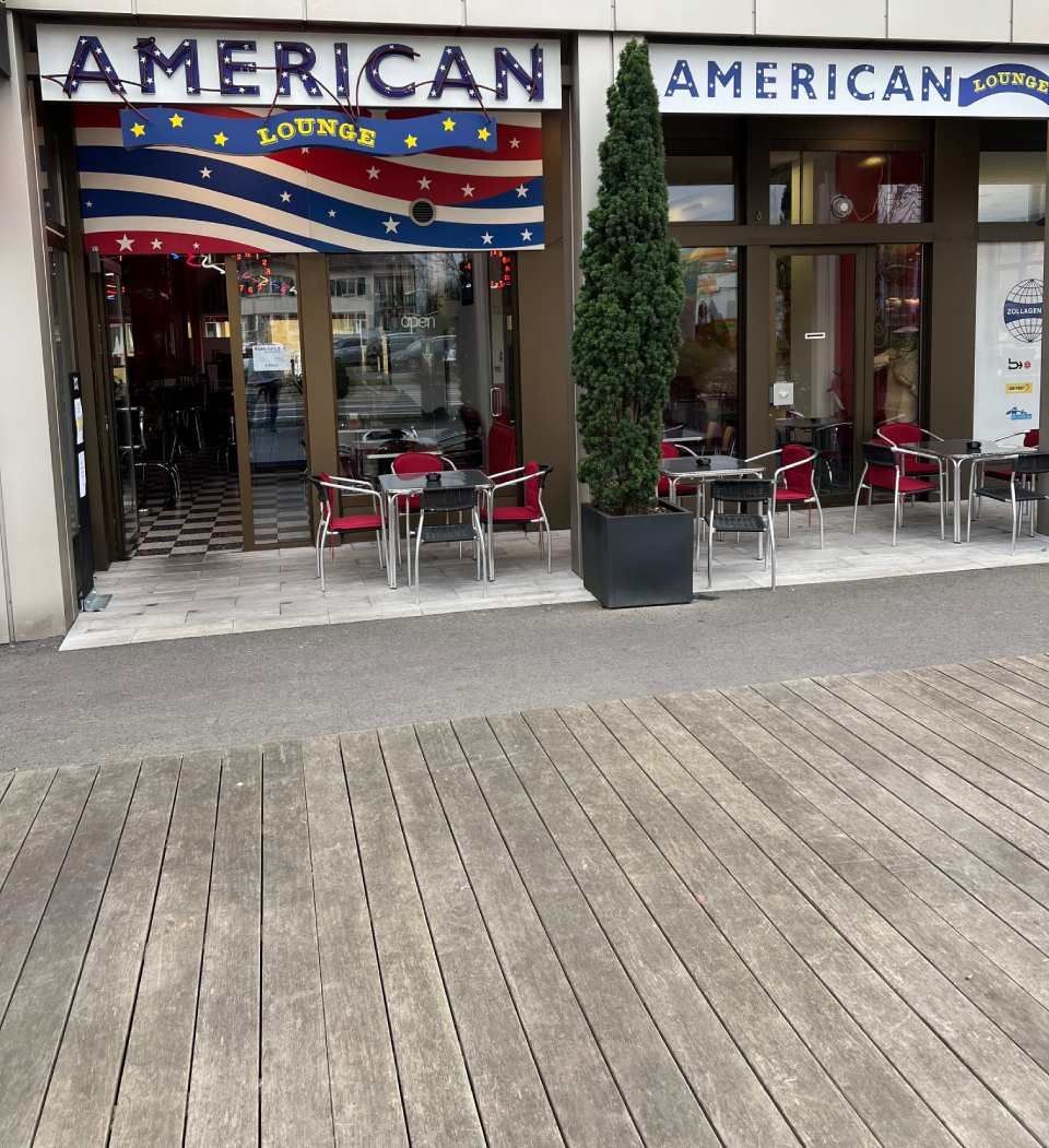 Die Aussenseite eines amerikanischen Restaurants mit Tischen und Stühlen.