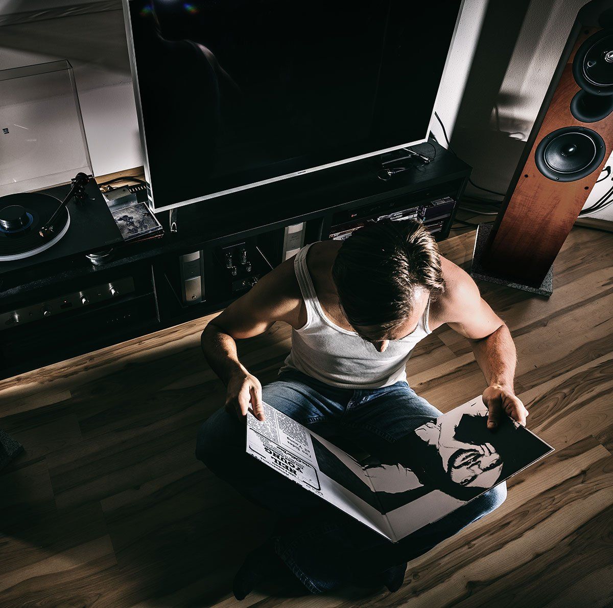 Hiomme qui regarde un vinyle en écoutant de la musique