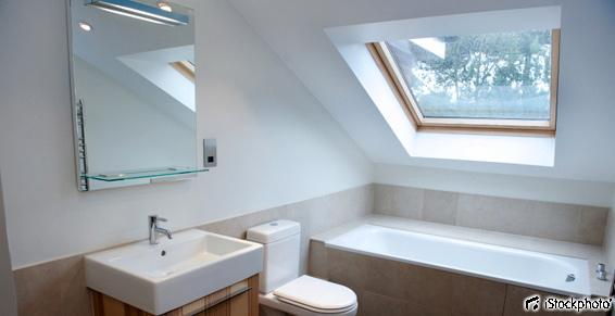 Salle de bains moderne avec lavabo, toilettes, baignoire et fenêtre de toit.