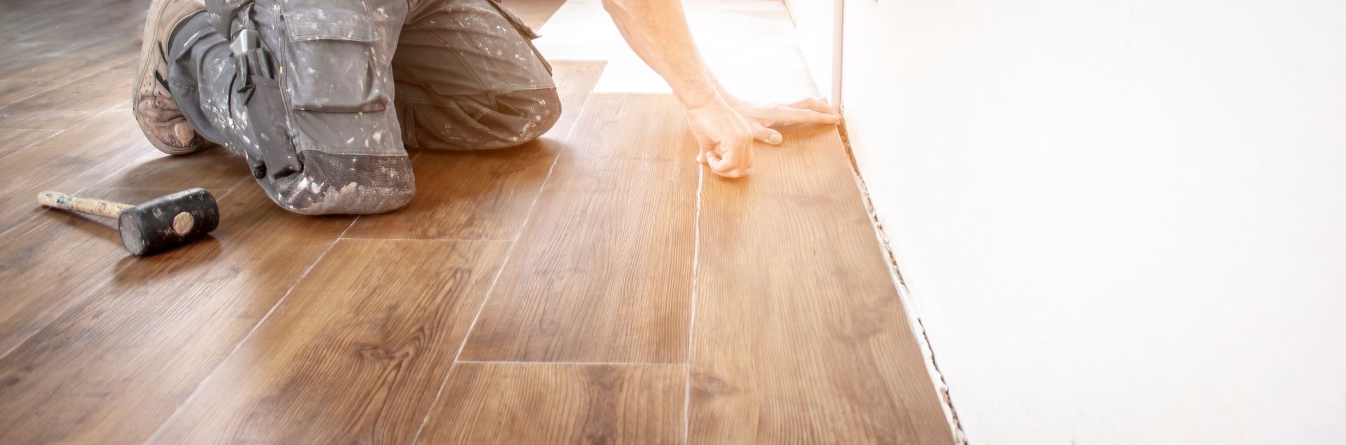 Un artisan posant un sol vinyle imitation parquet.