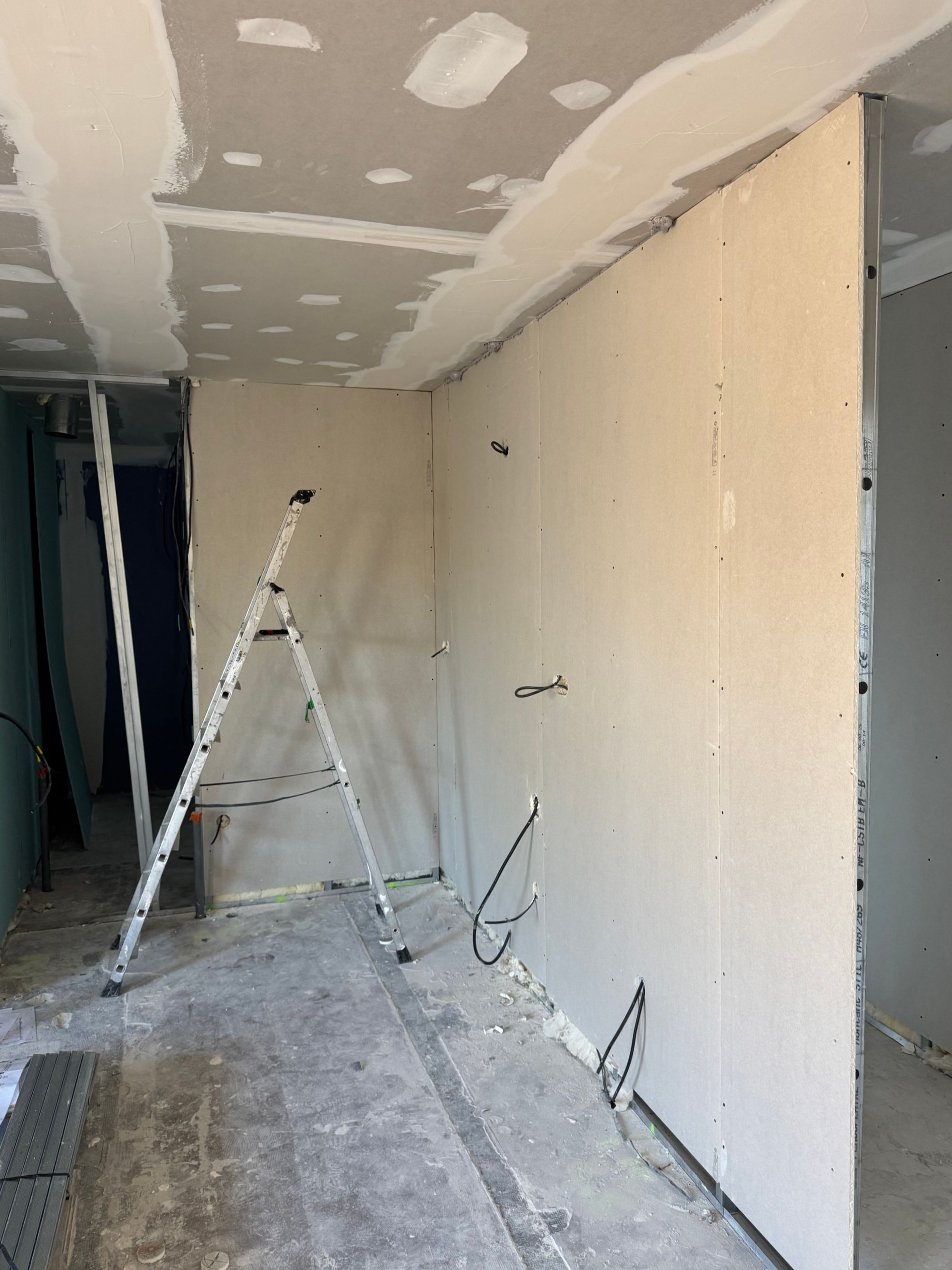 Couloir partiellement rénové avec des cloisons sèches et un escabeau.