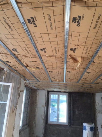 Pièce en construction avec plafond dont l'isolation est apparente.